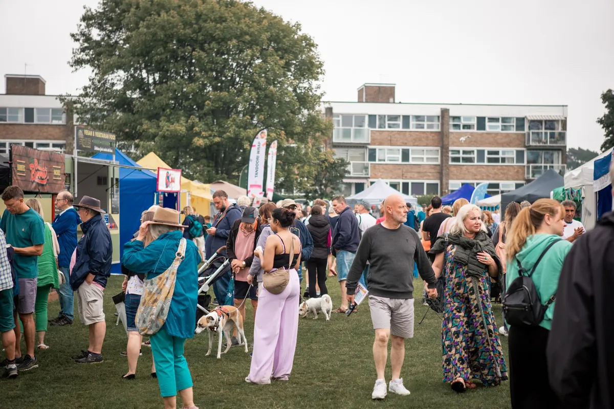 Visitors walking between festival stalls on a town green